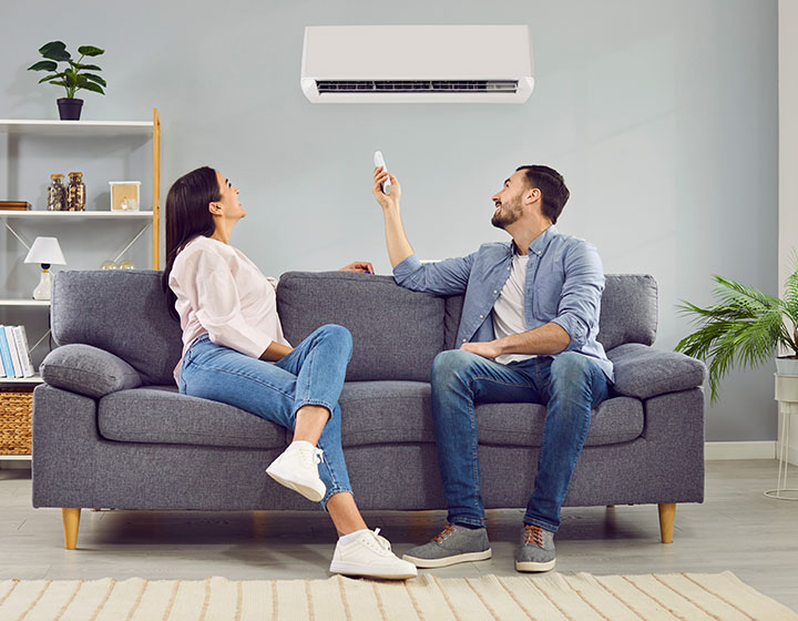 couple sitting on couch adjusting heat pump settings