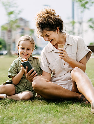 Mom and child with ice cream looking at phone.