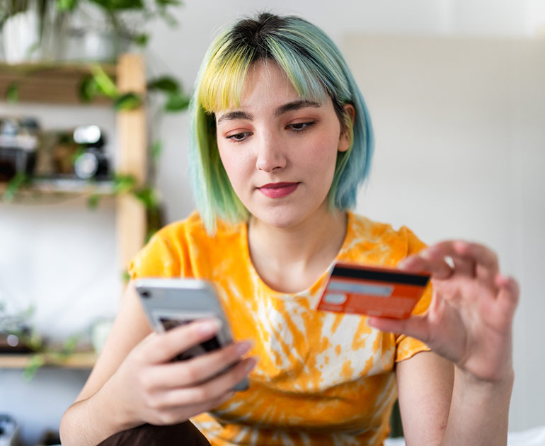 Girl looking at credit card and phone.