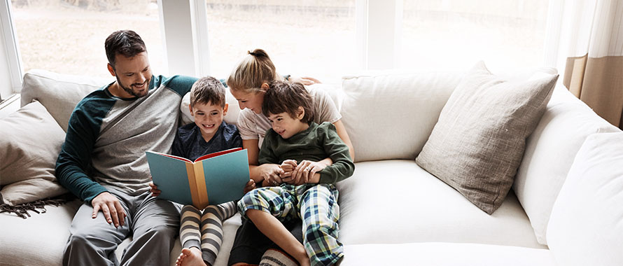 family sitting on couch reading a book