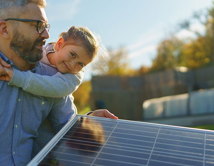 girl on father's back looking at solar panels