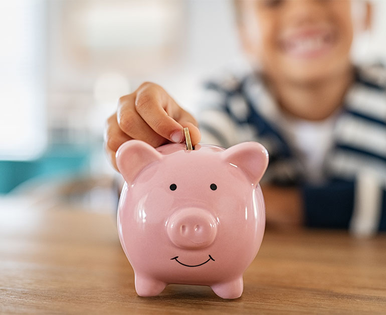 child putting money in piggy bank