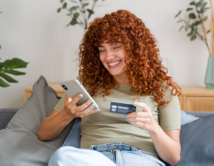 Woman at home with credit card and phone.