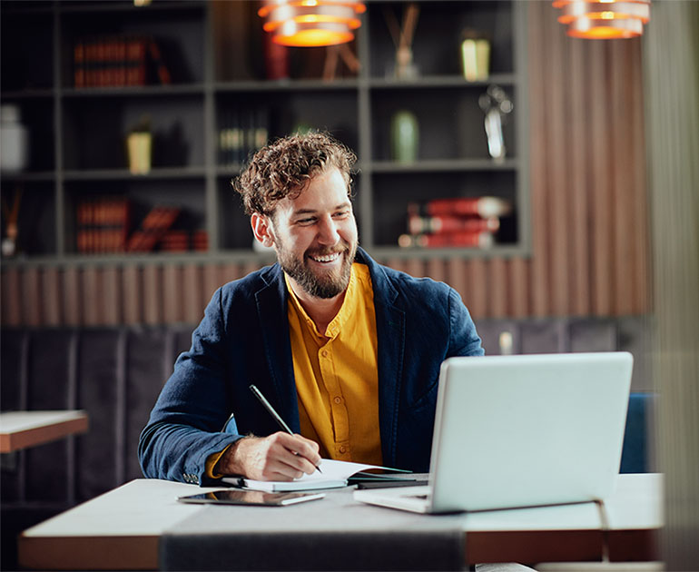 man sitting at table on laptop