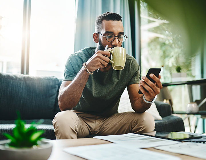 Man sipping coffee looking at phone